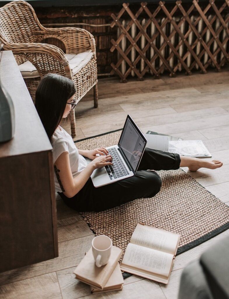Woman seated on floor with laptop.